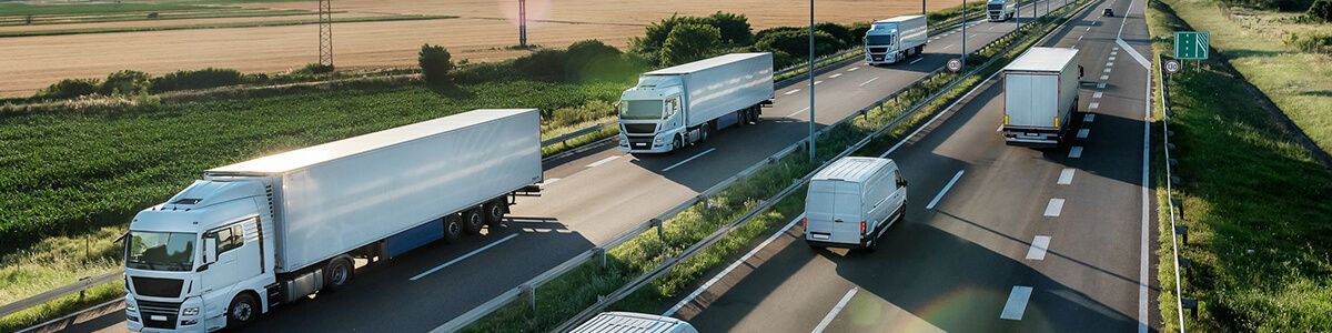 An overhead view of two two-lane roads with semi-trucks and vans driving by